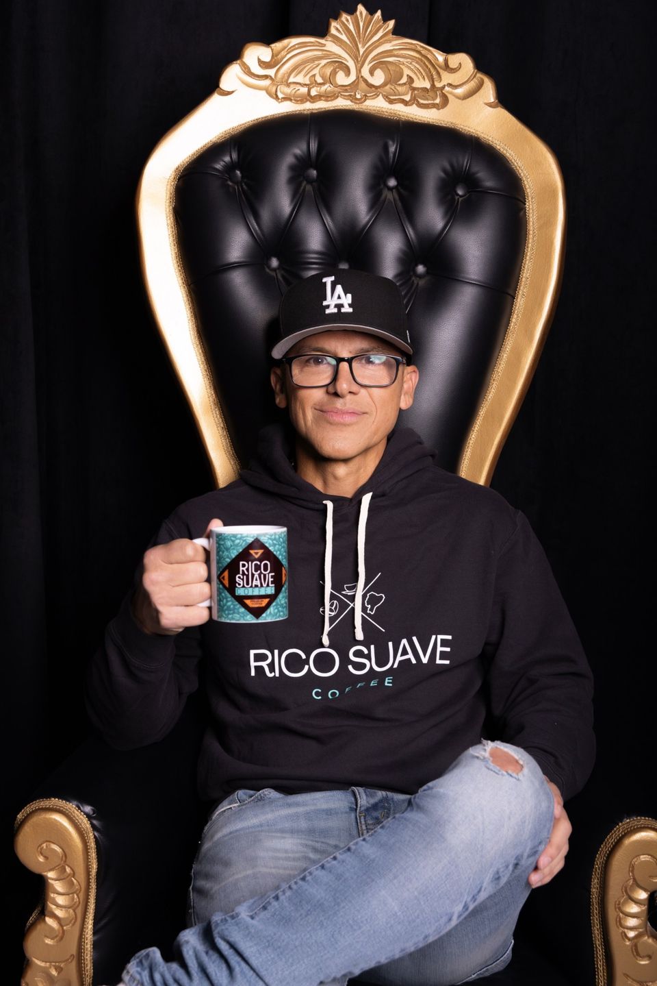 Gerardo Mejía on a gold throne, holding a Rico Suave Coffee mug